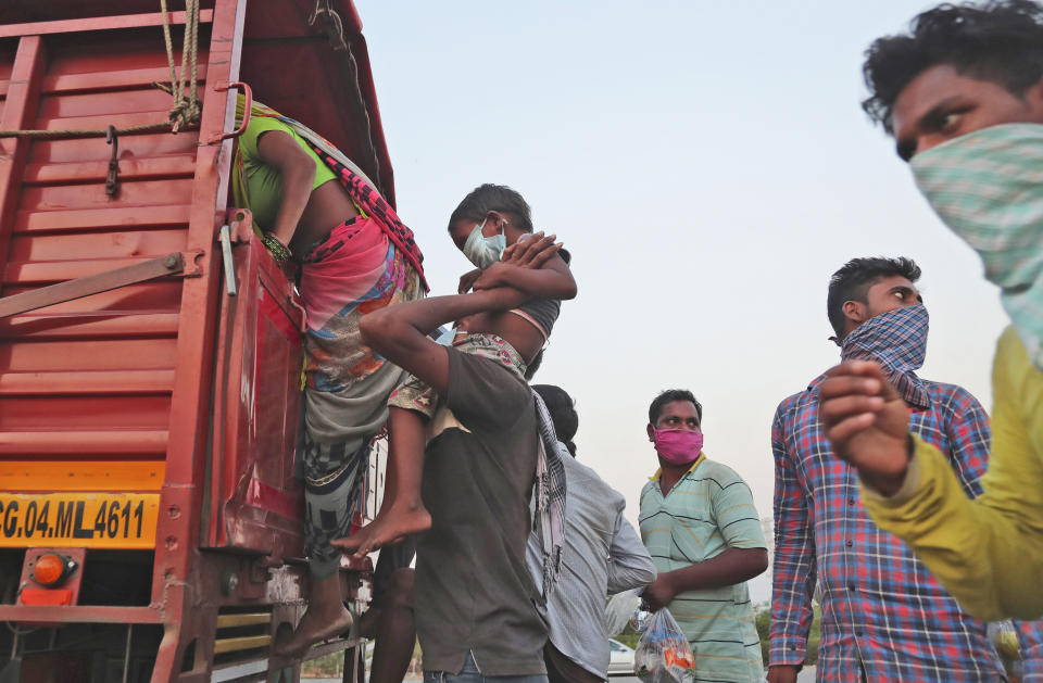 In this Tuesday, May 12, 2020, photo, a migrant worker from Chhattisgarh state helps a child climb onto a truck to travel to their villages hundreds of miles away during a nationwide lockdown to curb the spread of new coronavirus on the outskirts of Hyderabad, India. Tens of thousands of impoverished migrant workers are on the move across India, walking on highways and railway tracks or riding trucks, buses and crowded trains in blazing heat amid threat to their lives from the coronavirus pandemic. (AP Photo/Mahesh Kumar A)