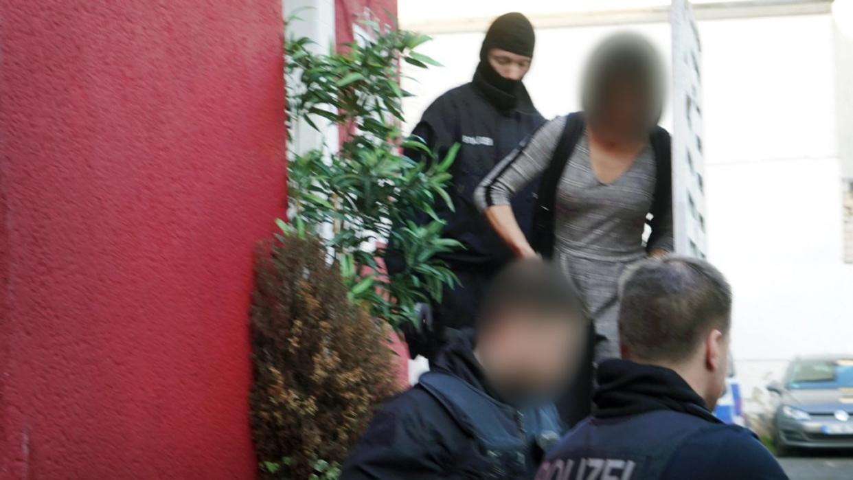 Polizisten führen in Bonn eine Person ab: Mehr als 100 Personen wurden bei der bundesweiten Aktion gegen eine Bande im Rotlichtmilieu vorläufig festgenommen. Foto: Axel Vogel