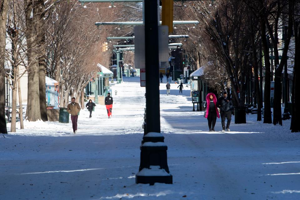 People walk down Main Street through the snow in Memphis, Tenn., on Tuesday, January 16, 2024.