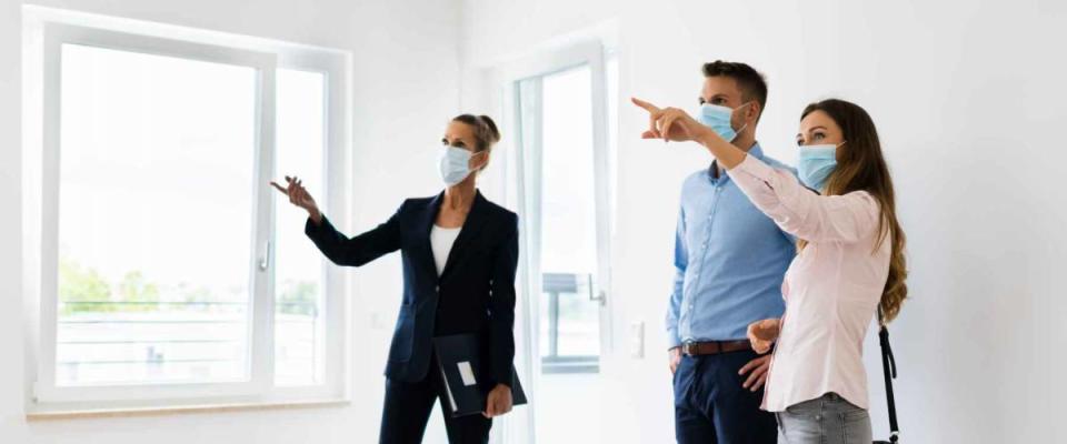 Happy Couple Buying New Home With Realtor Wearing Face Masks