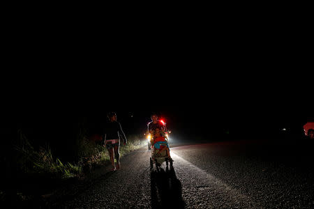 Eight months pregnant Honduran migrant Erly Marcial, 21, walks along the road that links Arriaga and Tapanatepec, with her husband Alvin Reyes, 39, carrying their children David, 2, and Maria, 6, near Arriaga, Mexico, November 5, 2018. REUTERS/Carlos Garcia Rawlins