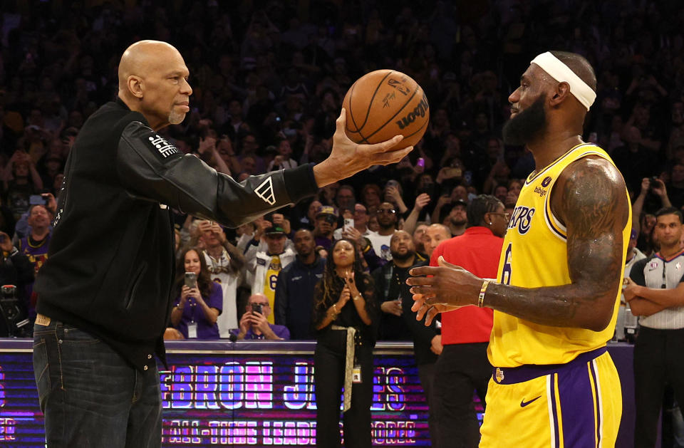 Kareem Abdul-Jabbar ceremoniously hands LeBron James the ball after James passed Abdul-Jabbar to become the NBA's all-time leading scorer, during the third quarter against the Oklahoma City Thunder at Crypto.com Arena in Los Angeles on Feb. 7, 2023. (Harry How/Getty Images)