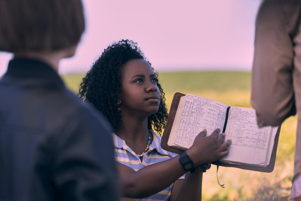 Camryn Jones (playing Tiffany Quilkin in Paper Girls) holds up a book of notes.