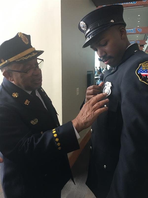 Thomas Lipscomb, a retired Nashville Fire Department assistant chief, pins a badge on his grandson Josh Lipscomb.