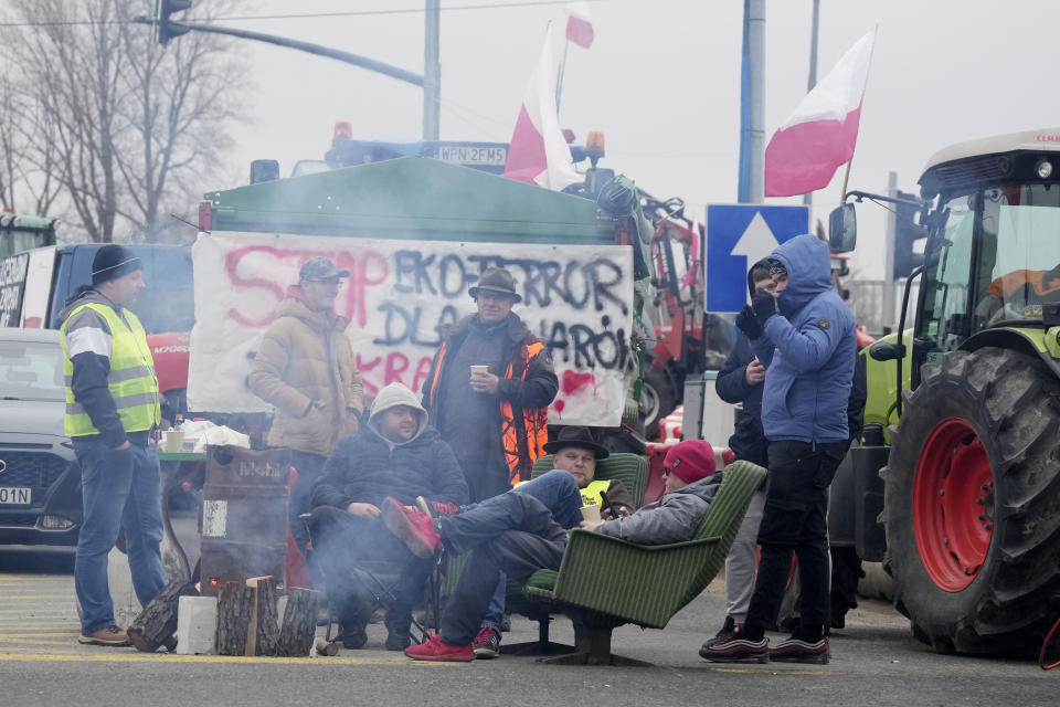 Polish protesters sit around a campfire in Kazun Polski near Warsaw, Poland, on Wednesday March 20, 2024 during a nationwide farmers' protest against Ukrainian imports and European Union climate policies. The calls of farmers across Europe have grown increasingly strident even though the European Commission has relented to their pressure by rolling back some environmental requirements. (AP Photo/Czarek Sokolowski)