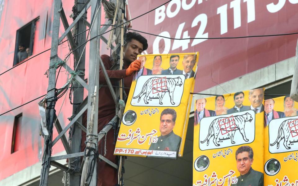 A worker installs posters of former Prime Minister Nawaz Sharif's Pakistan Muslim League Nawaz