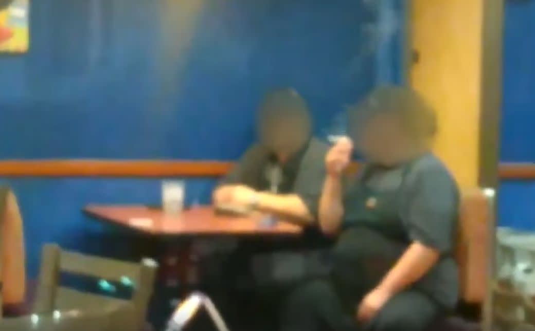 Two Taco Bell employees in North Carolina were captured on video smoking inside an empty store, despite a long line at the drive-thru. (Photo: Facebook)