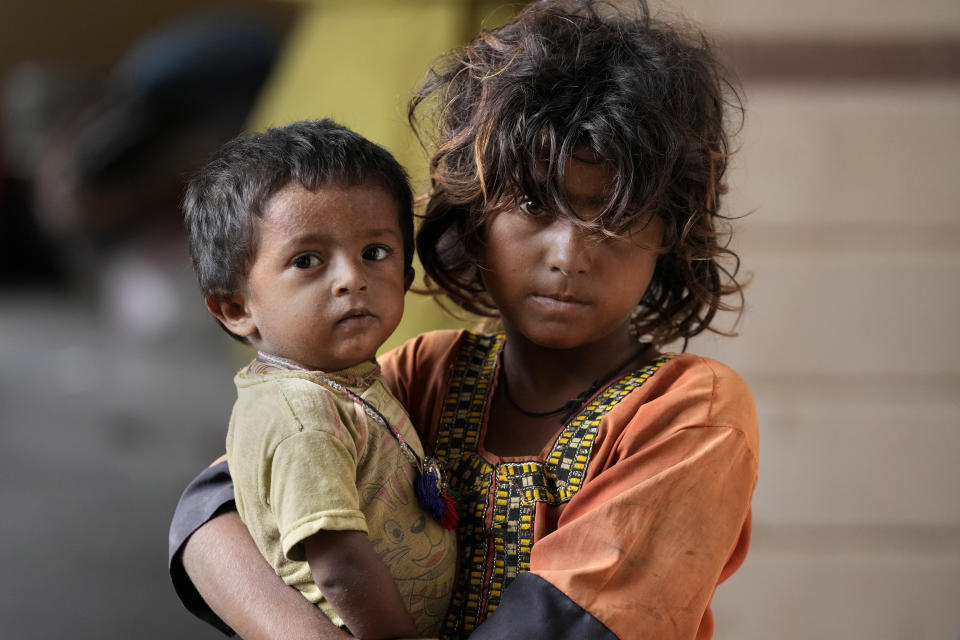 A girl holds her younger brother as she with her family take shelter in a school after fleeing from their villages of costal areas due to Cyclone Biparjoy approaching, in Gharo near Thatta, a Pakistan's southern district in the Sindh province, Wednesday, June 14, 2023. In Pakistan, despite strong winds and rain, authorities said people from vulnerable areas have been moved to safer places in southern Pakistan's districts. With Cyclone Biparjoy expected to make landfall Thursday evening, coastal regions of India and Pakistan are on high alert. (AP Photo/Fareed Khan)