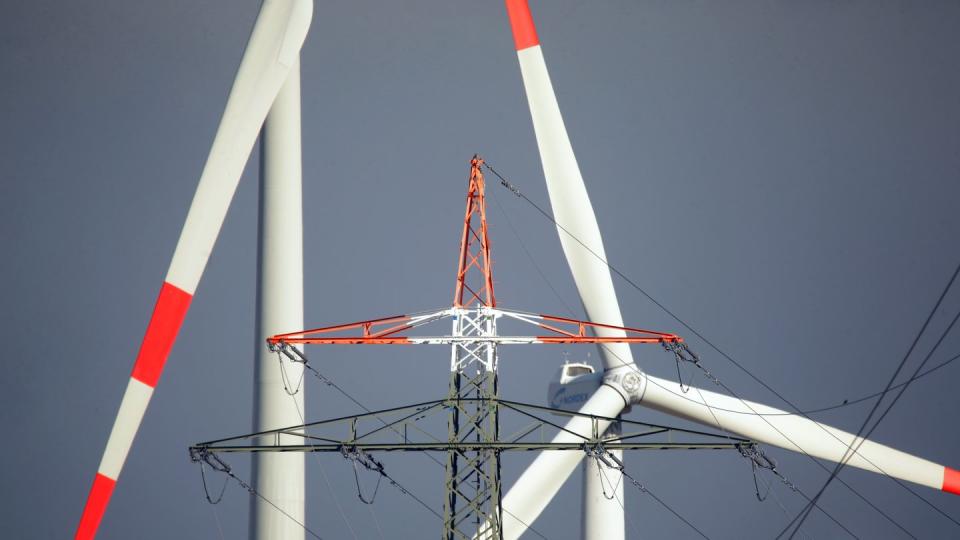 Windräder und ein Strommast stehen in Erkelenz. Die EEG-Umlage zur Förderung des Ökostroms wäre im nächsten Jahr auf ein Rekordhoch gestiegen - allerdings hat die Bundesregierung bereits eine Deckelung angekündigt.