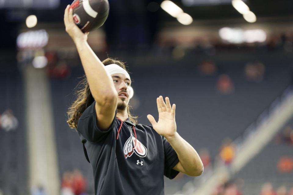 Utah Utes QB Cameron Rising, wearing black, warms up