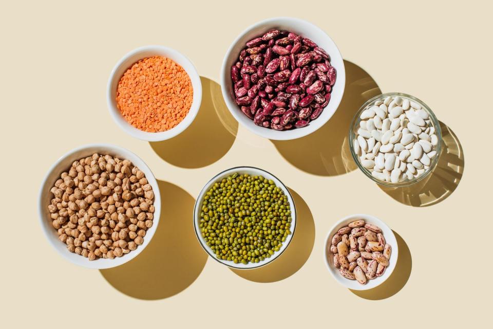 various kinds of vegan protein sources on beige background nuts and legumes green mung beans, chick pea, red lentil, kidney bean, almonds, hazelnuts flat lay, top view