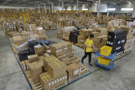 In this Saturday, June 15, 2019, photo, a worker passes by goods piled up at a warehouse in Nanjing in east China's Jiangsu province. China's economic growth slowed to its lowest level in a decade last quarter amid a tariff war with Washington, adding to pressure on Beijing to reverse a deepening slump. (Chinatopix via AP)