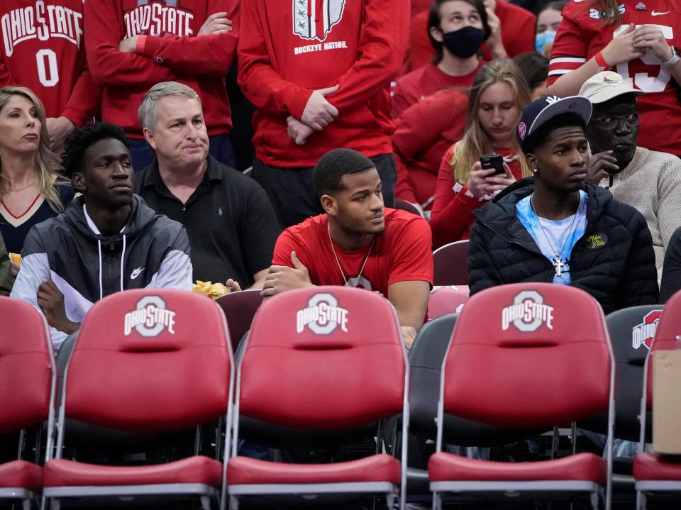 Ohio State basketball recruits, from left, Scotty Middleton, a 2023 recruit, Roddy Gayle Jr. and Felix Okpara, both 2022 commits, watch the Buckeyes warm up prior to the NCAA men's basketball game against the Michigan Wolverines at Value City Arena in Columbus on March 6, 2022. 