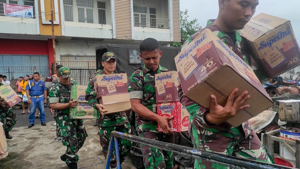 Indonesian military personnel load food onto a ship as they head to the island near Mount Ruang volcano in the port of Manado, North Sulawesi, on April 18, 2024