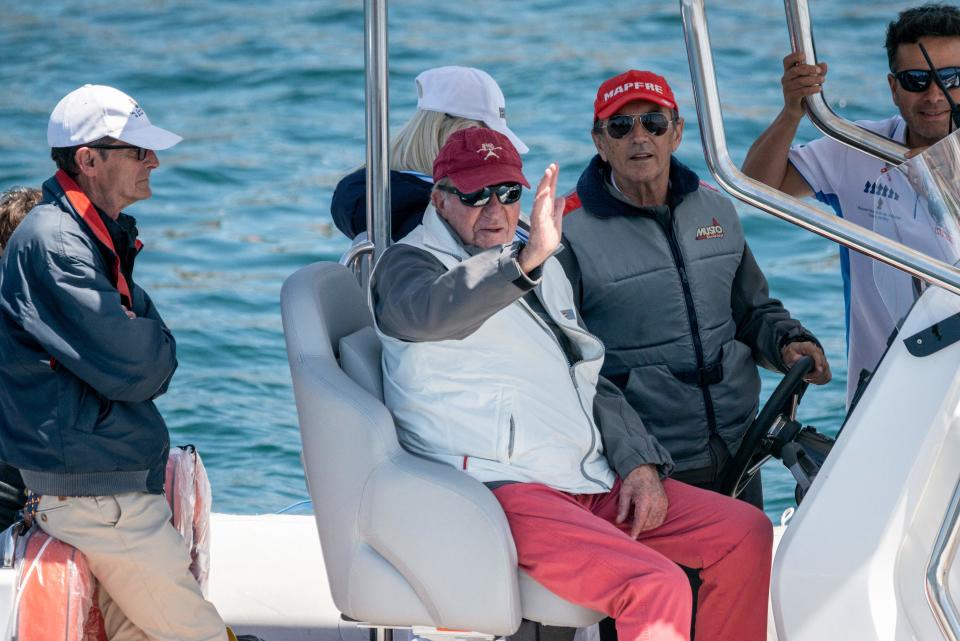 Spain's former King Juan Carlos I (C) waves from an inflatable boat sailing alongside his 