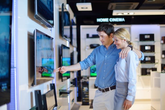 Man and woman looking at a TV in a store.