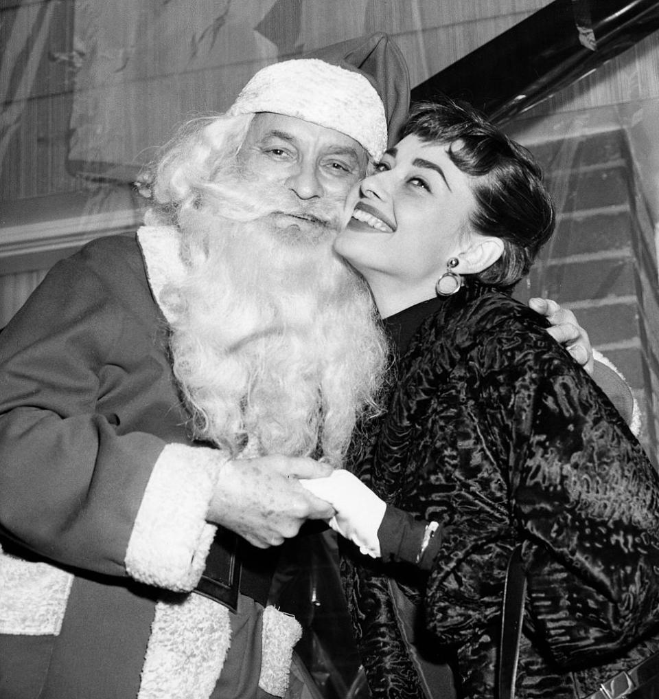 <p>Audrey Hepburn flashes a wide grin as she poses with Santa while at a charity event in New York City during the holidays. </p>