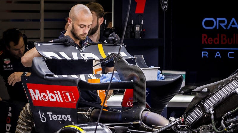A Red Bull Racing F1 mechanic fitting the rear-wing upper flap to a car.