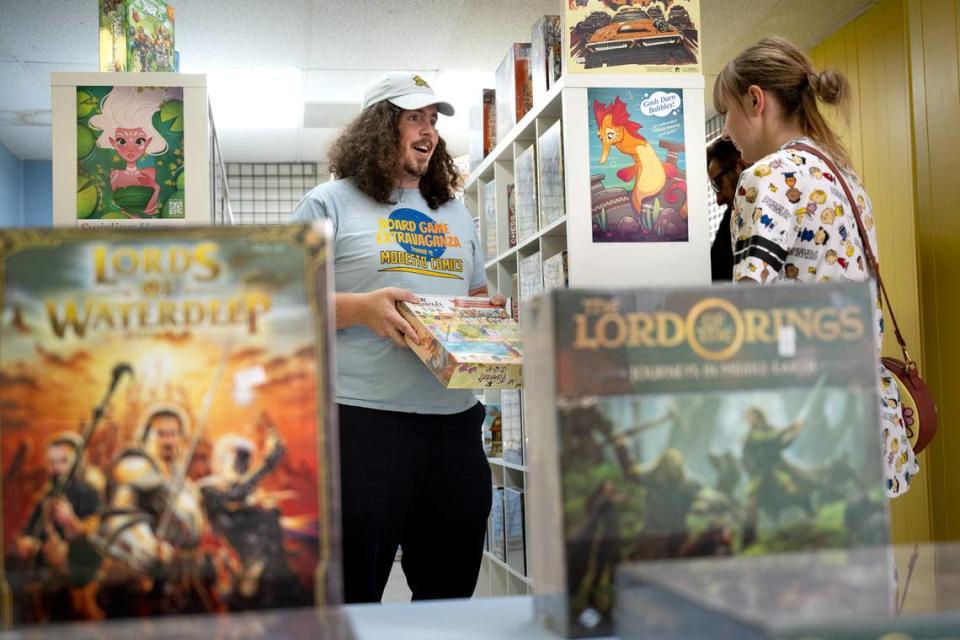 Rob Van Tuinen shows Heather Harless the game Flamecraft at Meeple Valley Board Game Cafe in Modesto, Calif., Thursday, March 21, 2024.