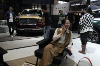 A woman chats on her phone near the Lincoln Navigator SUV during Auto China 2024 held in Beijing, Thursday, April 25, 2024. Global automakers and EV startups unveiled new models and concept cars at China's largest auto show on Thursday, with a focus on the nation's transformation into a major market and production base for digitally connected, new-energy vehicles. (AP Photo/Ng Han Guan)