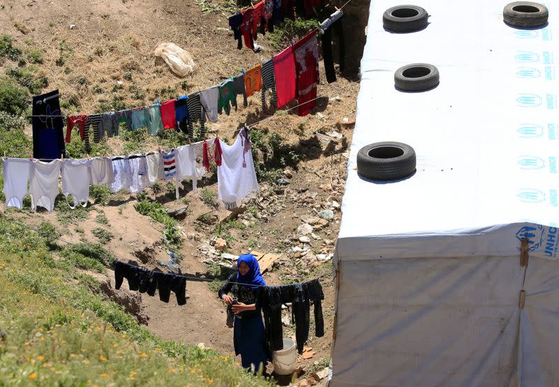 A Syrian refugee woman hangs clothes to dry, as Lebanon extends a lockdown to combat the spread of the coronavirus disease (COVID-19) at a Syrian refugee camp in the Bekaa valley