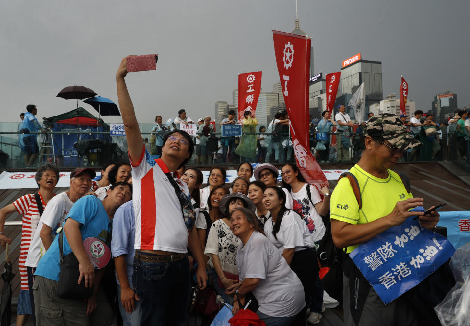 Pro-China supporters pose for a picture during a counter-rally in support of the police in Hong Kong Saturday, July 20, 2019. A counter-rally in support of the police was held Saturday evening. Thousands of people under umbrellas and overcast skies filled a park in central Hong Kong. (AP Photo/Vincent Yu)