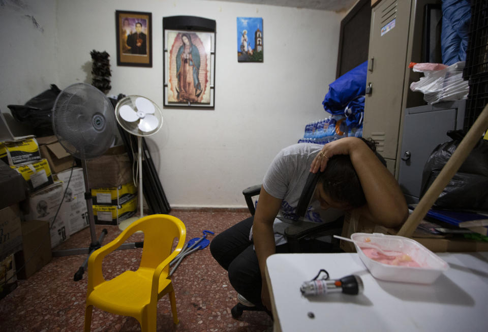 In this Sept. 18, 2019 photo, the wife of Nicaraguan migrant Yohan leans over a cell phone to speak with her family in Nicaragua, a she sits in the kitchen of a migrant shelter where she lives with her husband and son in Monterrey, Mexico. Linda's family left Nicaragua after armed, government-aligned civilian militias learned that Yohan had witnessed the killing of a government opponent, he said. They followed him and painted death threats on the walls of their home. (AP Photo/Fernando Llano)