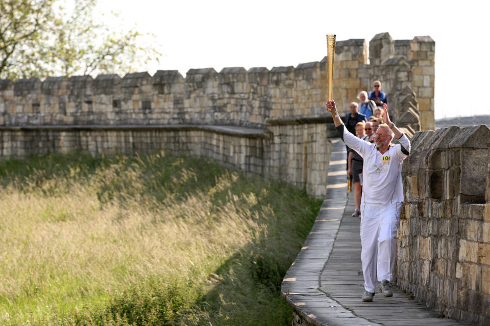 In this handout image provided by LOCOG, Torchbearer 104 Philip Jones carries the Olympic Flame on the York City Walls on the Torch Relay leg through York on June 19, 2012 in York, England. The Olympic Flame is now on day 32 of a 70-day relay involving 8,000 torchbearers covering 8,000 miles. (Photo by LOCOG via Getty Images)