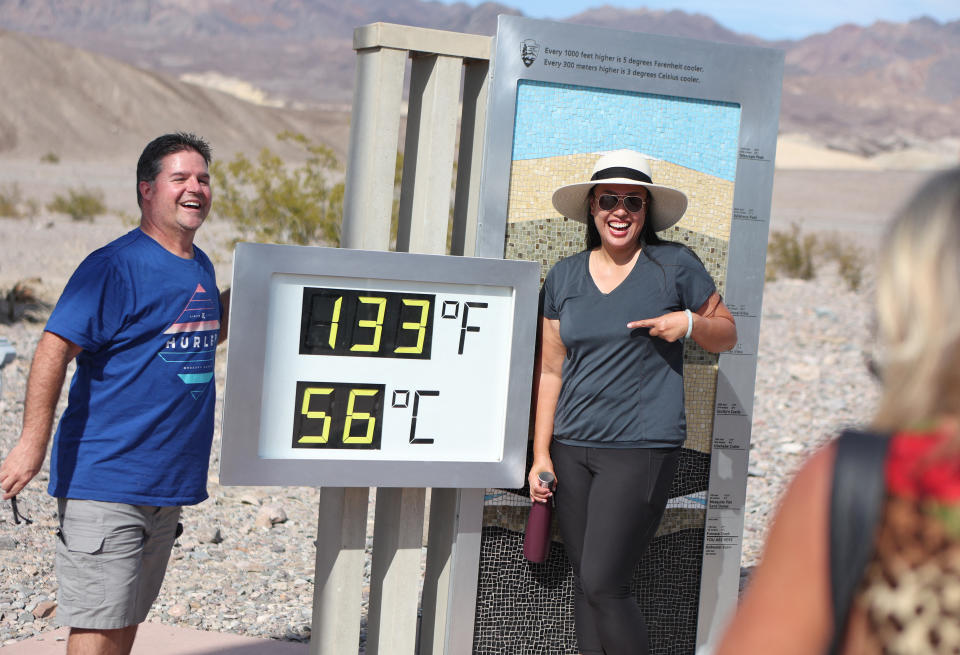 TOPSHOT - Clint Johnson, of Pleasant Hill, Calif., (L) and Melanie Anguay, of Las Vegas, stand for a photo next to a digital display of an unofficial heat reading at Furnace Creek Visitor Center during a heat wave in Death Valley National Park in Death Valley, California, on July 16, 2023. Tens of millions of Americans braced for more sweltering temperatures Sunday as brutal conditions threatened to break records due to a relentless heat dome that has baked parts of the country all week. By the afternoon of July 15, 2023, California's famous Death Valley, one of the hottest places on Earth, had reached a sizzling 124F (51C), with Sunday's peak predicted to soar as high as 129F (54C). Even overnight lows there could exceed 100F (38C). (Photo by Ronda Churchill / AFP) (Photo by RONDA CHURCHILL/AFP via Getty Images)