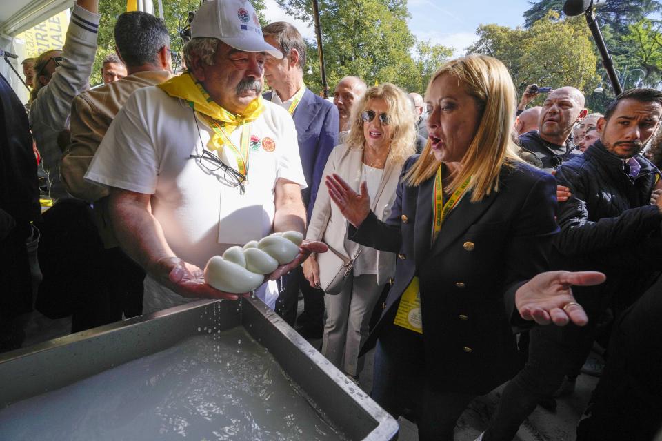 Brothers of Italy leader Giorgia Meloni looks at a farmer making mozzarella knots at the Coldiretti village Italian farmers association's event, in Milan, Italy, Saturday, Oct. 1, 2022. (AP Photo/Luca Bruno)