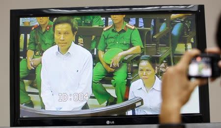 A journalist takes a photo of a live screen from the courtroom showing Vietnamese prominent blogger Anh Ba Sam whose real name is Nguyen Huu Vinh (L), and his assistant Nguyen Thi Minh Thuy, during their appeal trial in Hanoi, Vietnam September 22, 2016. REUTERS/Kham