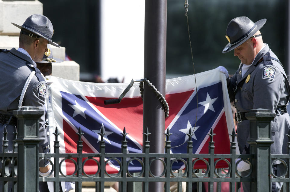 FILE - In this July 10, 2015, file photo, members of an honor guard from the South Carolina Highway patrol lower the Confederate battle flag as it is removed from the Capitol grounds in Columbia, S.C. Confederate Relic Room Executive Director Allen Roberson said Tuesday, Jan. 22, 2019, museum staff put the flag into a $1,400 protective case on Nov. 26, ending a more than three-year saga. (AP Photo/John Bazemore, File)