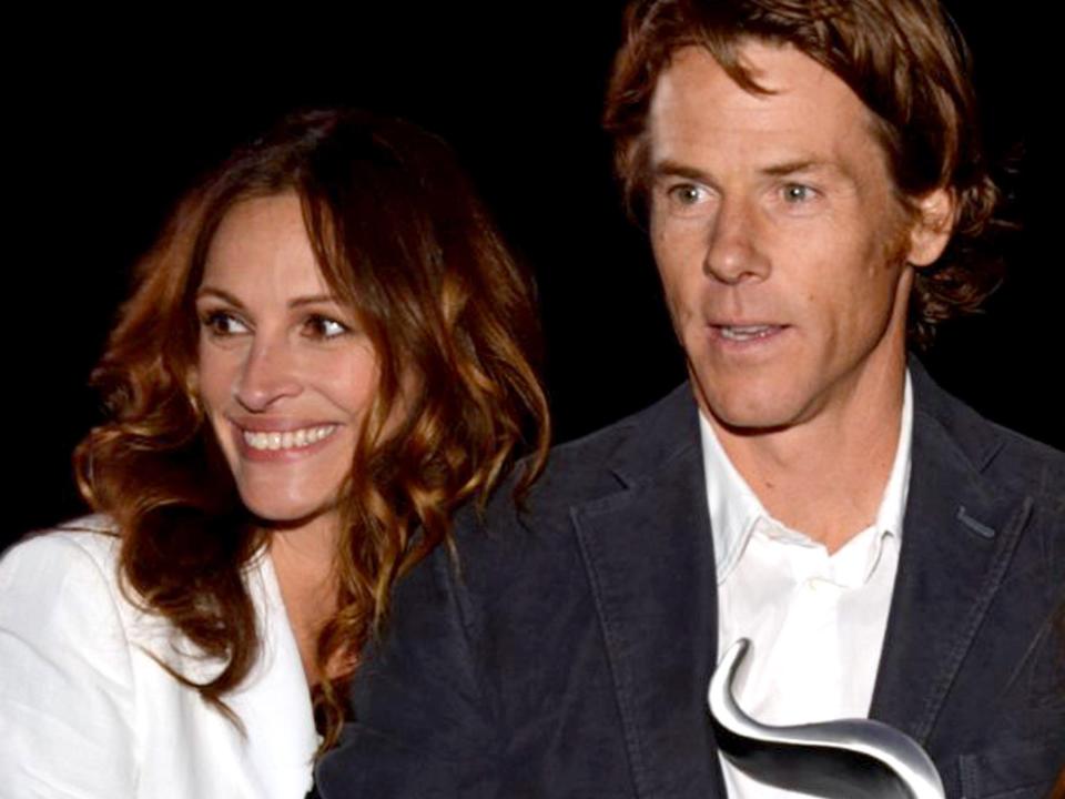 Julia Roberts, in a white blazer, and husband Danny Moder, in a dark jacket and holding an award, are pictured in this candid photo from a 2012 event.