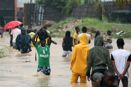 Residents wade through a flooded road in the aftermath of Cyclone Kenneth in Pemba, Mozambique, April 28, 2019. REUTERS/Mike Hutchings/Files