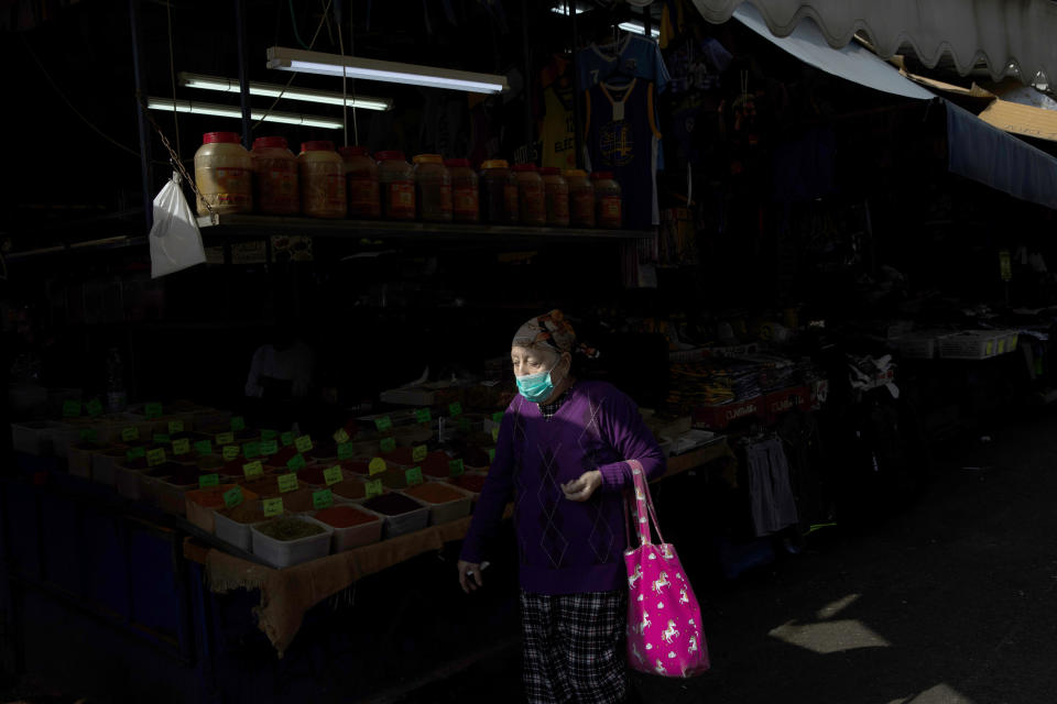 An elderly woman wears a face mask as she shops at a food market in Tel Aviv, Israel, Sunday, March 15, 2020. Israel has imposed a number of tough restrictions to slow the spread of the new coronavirus. Prime Minister Benjamin Netanyahu announced that schools, universities, restaurants and places of entertainment will be closed to stop the spread of the coronavirus. He also encouraged people not to go to their workplaces unless absolutely necessary. (AP Photo/Oded Balilty)