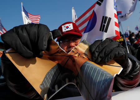 A demonstrator tears a portrait of North Korean leader Kim Jong Un during an anti-North Korea protest before the opening ceremony for the Pyeongchang 2018 Winter Olympics in Pyeongchang, South Korea, February 9, 2018. REUTERS/Edgar Su