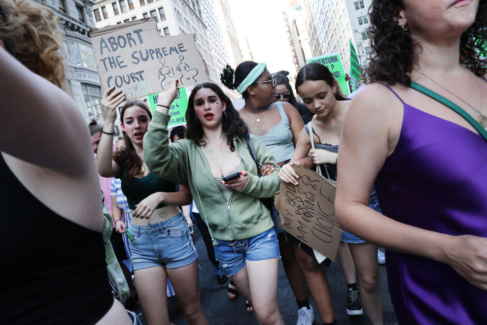 Protesters march, one with the sign "Abort the Supreme Court"