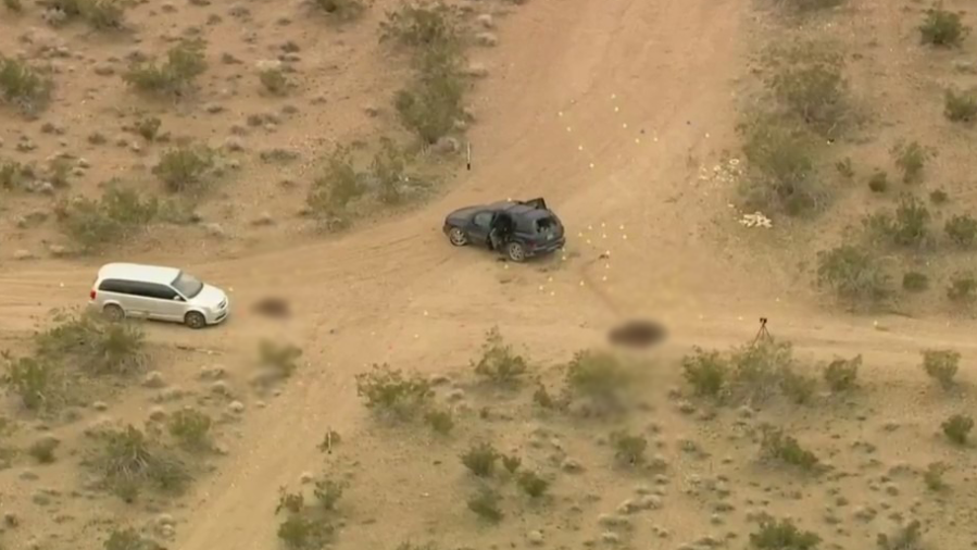 A SUV is seen riddled with bullet holes and surrounded by evidence markers in the Mojave Desert near Victorville, California on Jan. 24, 2024. (KTLA)