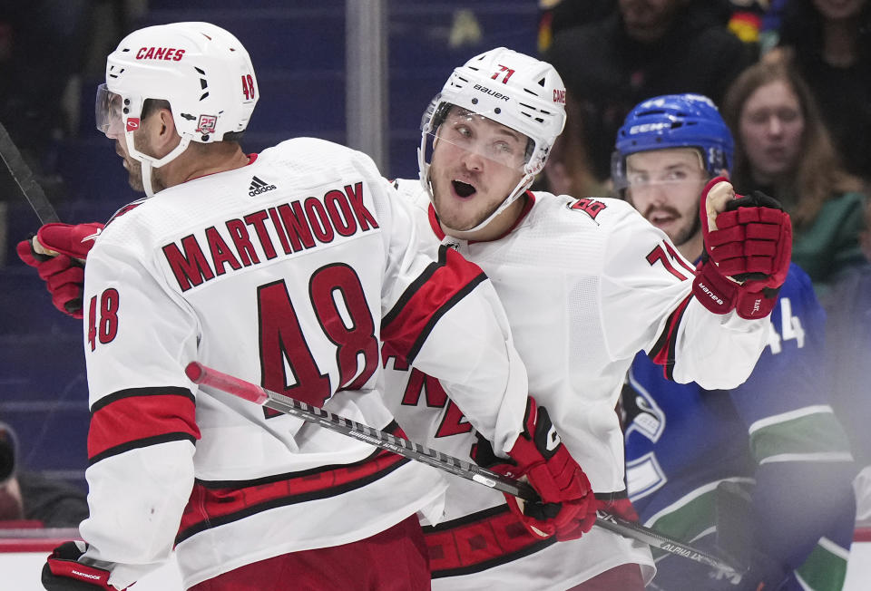 Carolina Hurricanes' Jesper Fast (71), of Sweden, celebrates his goal with Jordan Martinook (48) as Vancouver Canucks' Kyle Burroughs (44) skates to the bench during the third period of an NHL hockey game in Vancouver, British Columbia, Monday, Oct. 24, 2022. (Darryl Dyck/The Canadian Press via AP)