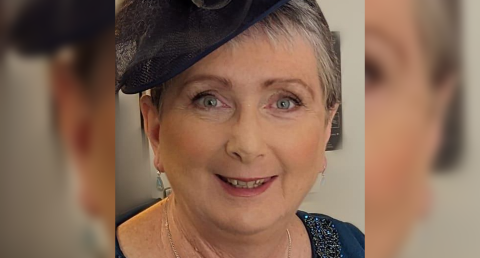 Brisbane woman Tracey Schwass wears a fascinator on her head and smiles at the camera.  