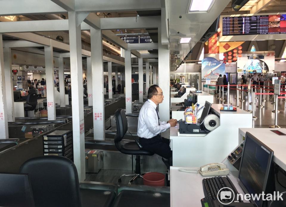 華航高雄小港國際機場上午多班次航班取消，圖為一位華航地勤人員坐在空蕩蕩的報到櫃檯內。   圖：張良一攝