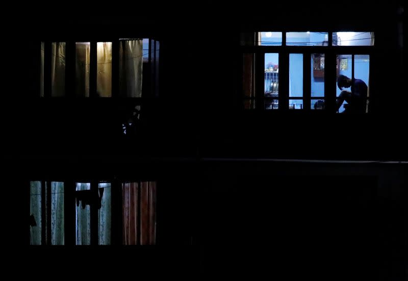 A man is silhouetted as he sits near the window of a house during the fifth day of the lockdown imposed by the government amid concerns about the spread of coronavirus disease (COVID-19), in Kathmandu