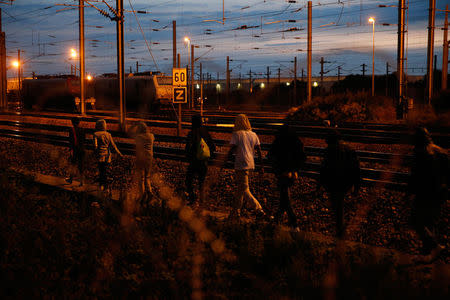 Migrants walk in single file along the train tracks near the Channel Tunnel access in Frethun, near Calais, France, August 3, 2015. REUTERS/Pascal Rossignol