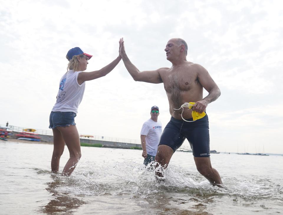 Stu Seltzer from Mamaroneck gives a high-five to a volunteer as he exits the water as over 500 swimmers take part in Swim Across America open water swim in Larchmont to raise funds for cancer research, clinical trials and client services on Saturday, July 29, 2023.