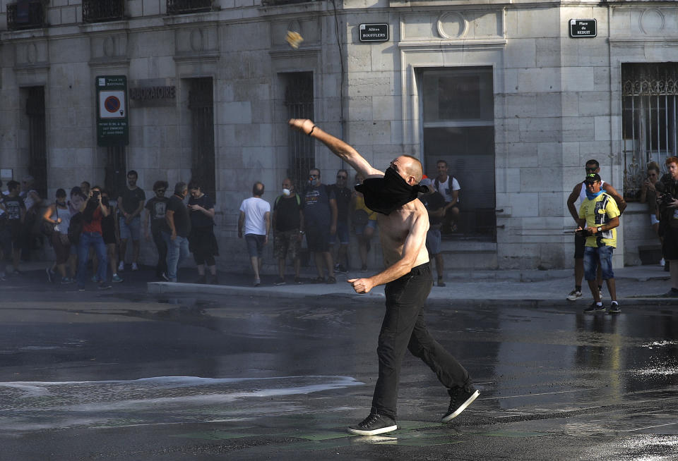 A protestor throws a rock at police in Bayonne, France, Saturday, Aug. 24, 2019. World leaders and protesters are converging on the southern French resort town of Biarritz for the G-7 summit. Police have fired water cannon at about 400 anti-capitalist protesters blocking roads in a town near the venue of the G-7 summit. A few protesters threw rocks at police but the crowd in Bayonne was largely peaceful. (AP Photo/Emilio Morenatti)