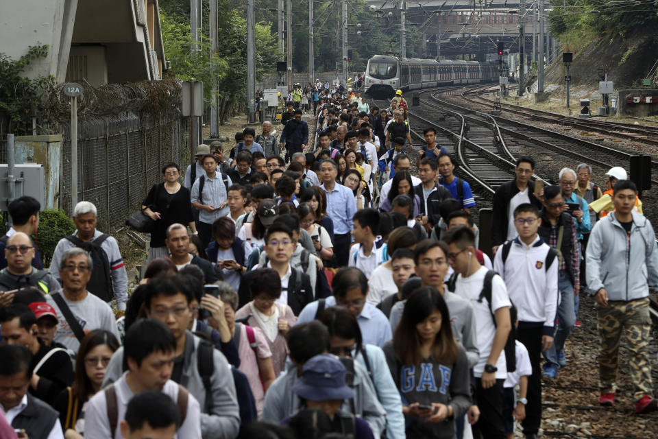 Commuters walk on the railway after their train service is disrupted by pro-democracy protesters in Hong Kong, Tuesday, Nov. 12, 2019. Protesters disrupted the morning commute in Hong Kong on Tuesday after an especially violent day in the Chinese city that has been wracked by anti-government protests for more than five months. (AP Photo)