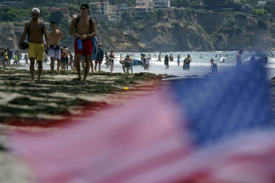 FILE - In this July 1, 2021, file photo, people walk along La Jolla Shores beach as Independence Day weekend nears in San Diego. Americans enjoying newfound liberty are expected to travel and gather for cookouts, fireworks and family reunions over the Fourth of July weekend in numbers not seen since pre-pandemic days. (AP Photo/Gregory Bull, File)