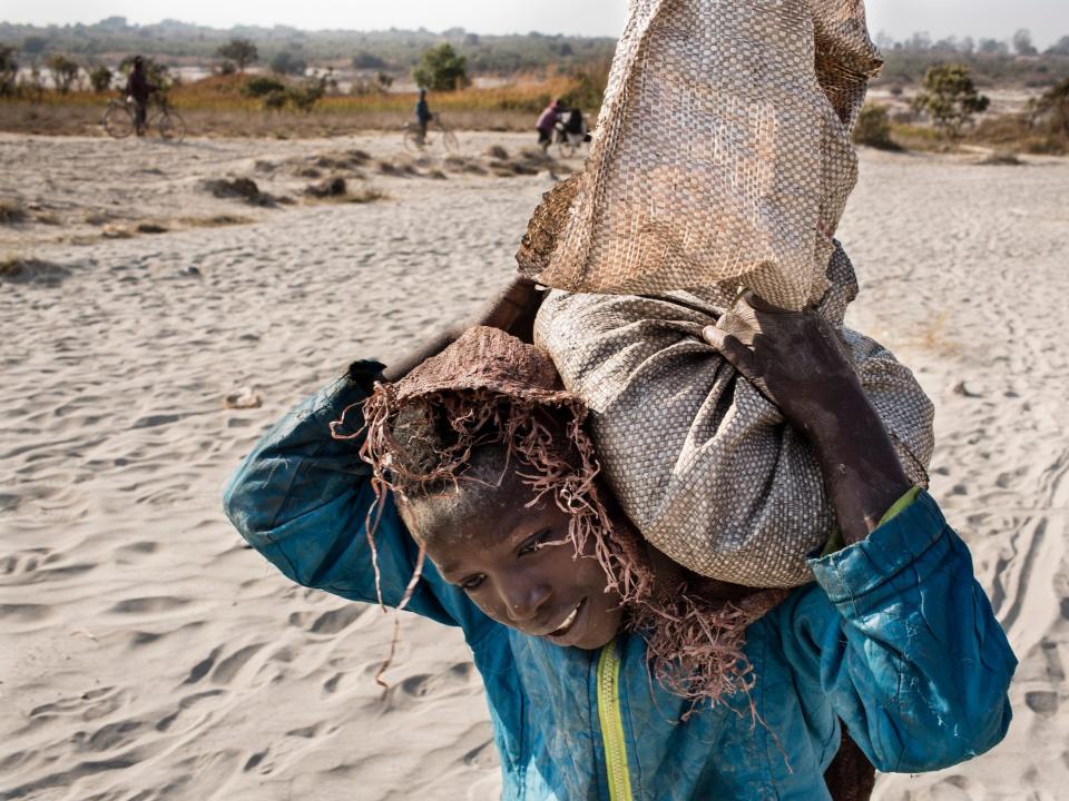 An 11-year-old named Daniel carries a bag of cobalt on his back