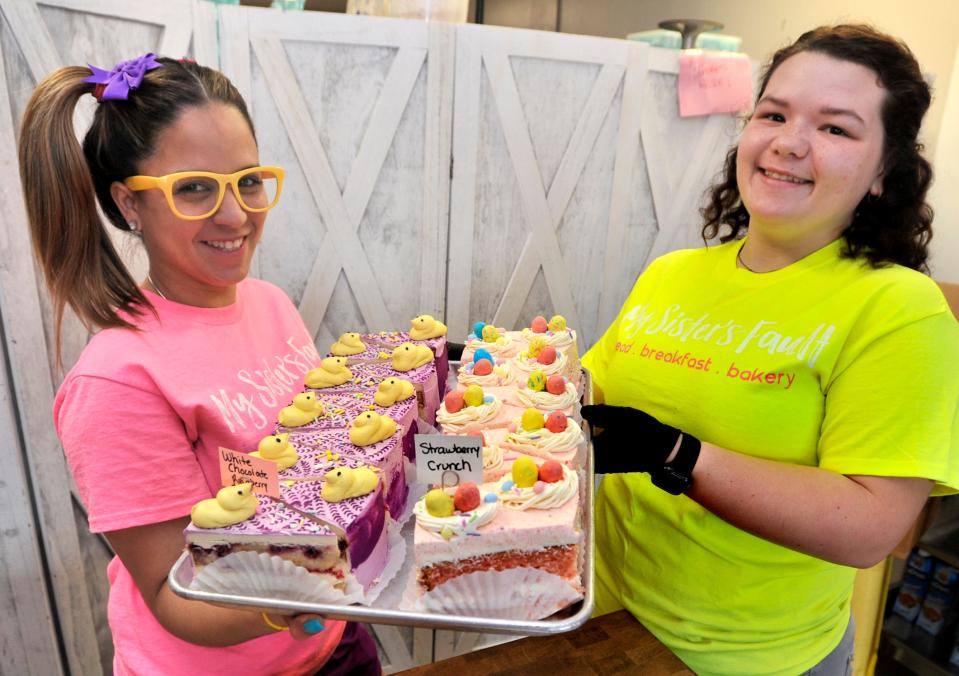 Family members Jesmarie Santiago (left) and Evelynn Gonzales setting up bakery items at My Sister's Fault in Milford.