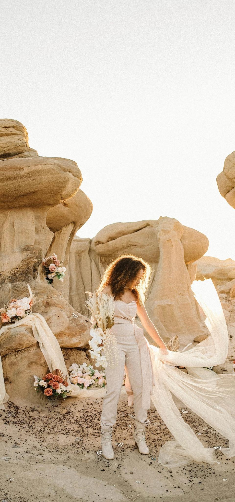 A bride poses in her wedding outfit in a desert.